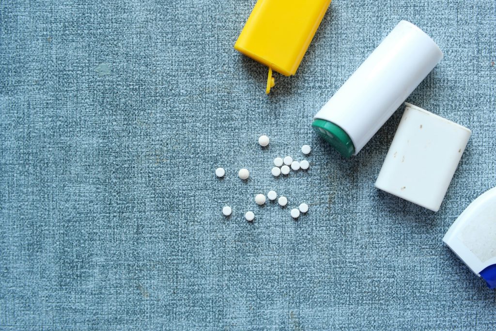 Top view of assorted pill containers and medication on a denim-like fabric surface.