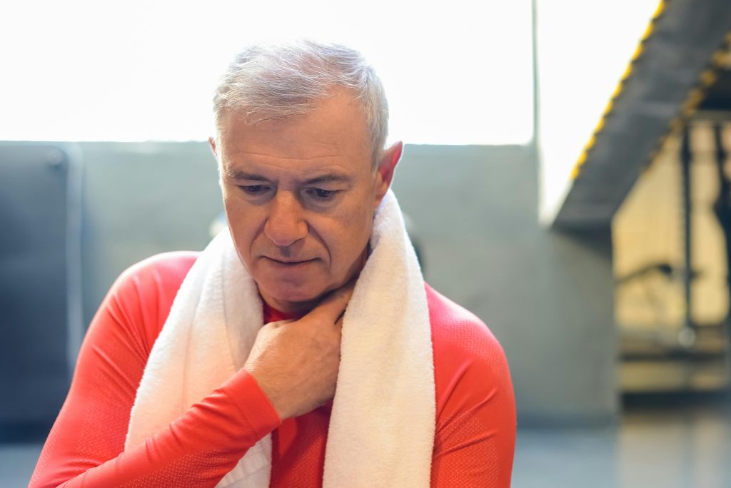 Senior man in gym resting with towel after exercise, Portugal.